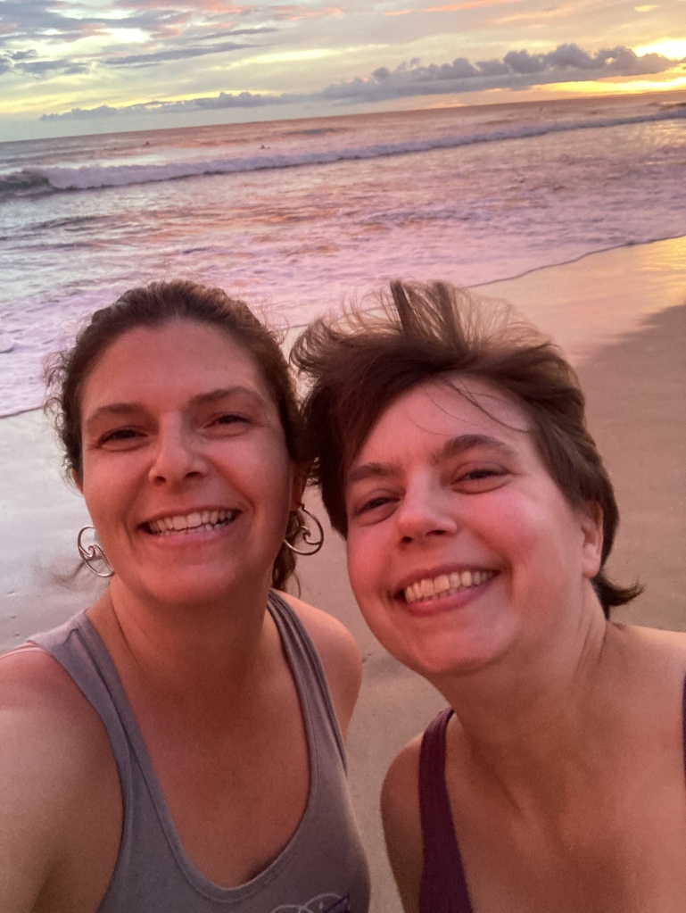 Two women smiling on a beach.